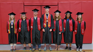 Class of 2018 standing inside the gym in their caps & gowns